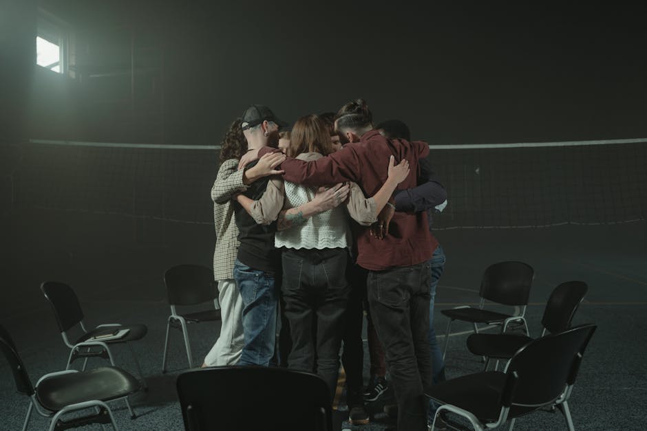 pexels-photo-5711000-5711000 A group of people embracing in a large room, symbolizing unity and emotional support.